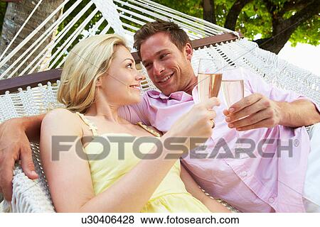 Couple Relaxing In Beach Hammock Drinking Champagne View Large Photo Image Stock Photo - Couple Relaxing In Beach Hammock Drinking Champagne. Fotosearch