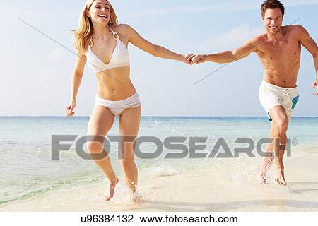 Couple Running Through Waves On Beach Holiday View Large Photo Image Stock Image - Couple Running Through Waves On Beach Holiday. Fotosearch