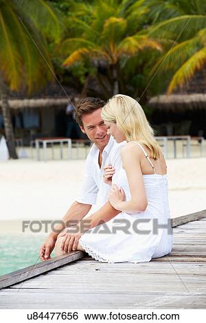 Stock Photograph - Couple Sitting On Wooden Jetty. Fotosearch