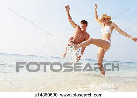 Couple Splashing In Sea On Beach Holiday View Large Photo Image Stock Photo - Couple Splashing In Sea On Beach Holiday. Fotosearch