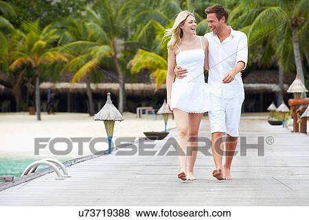Stock Photo - Couple Walking On Wooden Jetty. Fotosearch