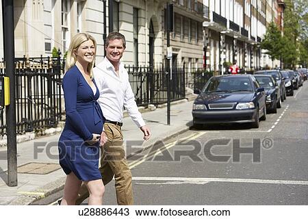 Stock Image - Couple With Pregnant Wife Crossing City Road. Fotosearch