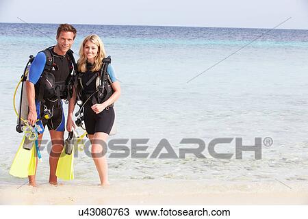 Stock Image - Couple With Scuba Diving Equipment Enjoying Beach Holiday. Fotosearch
