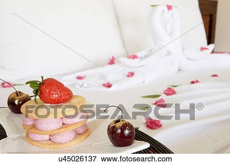 Dessert On Plate Next To Decorated Hotel Bed View Large Photo Image Stock Photo - Dessert On Plate Next To Decorated Hotel Bed. Fotosearch