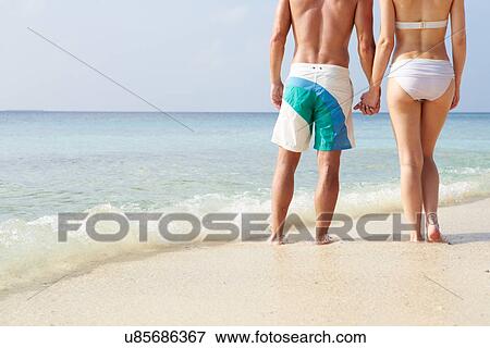 Stock Photo - Detail Of Couple Holding Hands On Beach Holiday. Fotosearch