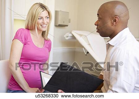 Stock Image - Doctor Using Digital Tablet In Meeting With Pregnant Woman. Fotosearch