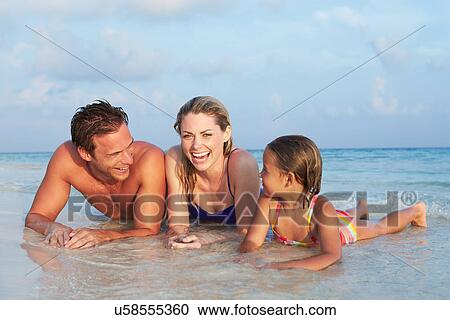 Stock Image - Family Lying In Sea On Tropical Beach Holiday. Fotosearch