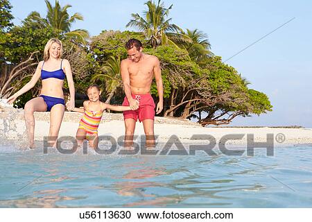 Stock Image - Family Splashing In The Sea On Tropical Beach Holiday. Fotosearch