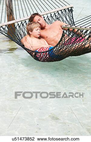 Stock Image - Father And Son Relaxing In Beach Hammock . Fotosearch