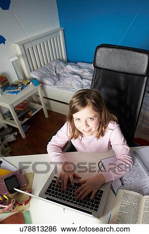 Stock Photograph - Girl Studying In Bedroom Using Laptop. Fotosearch