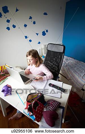 Stock Photograph - Girl Studying In Bedroom Using Laptop. Fotosearch