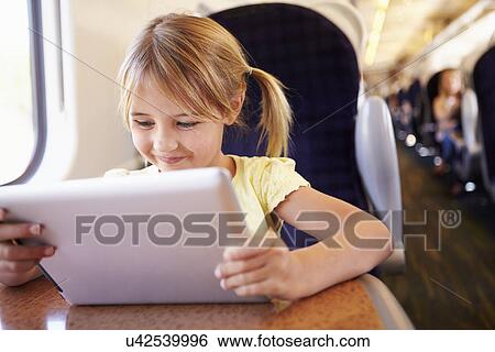 Stock Photograph - Girl Using Digital Tablet On Train. Fotosearch