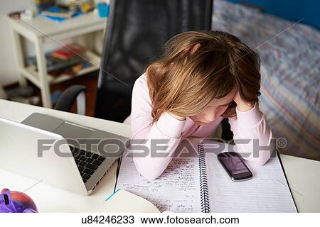 Stock Image - Girl Using Mobile Phone Instead Of Studying In Bedroom . Fotosearch