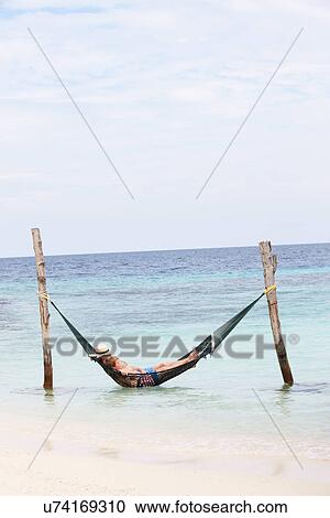 Stock Image - Grandfather And Grandson Relaxing In Beach Hammock . Fotosearch