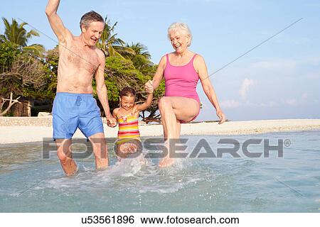 Grandparents With Granddaughter Splashing In Sea On Beach View Large Photo Image Stock Photograph - Grandparents With Granddaughter Splashing In Sea On Beach. Fotosearch