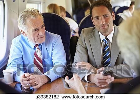 Stock Image - Group Of Businesspeople Having Meeting On Train. Fotosearch