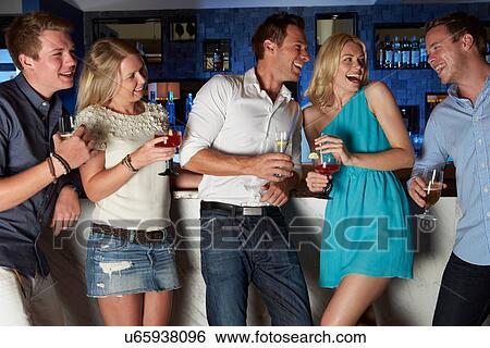 Stock Photograph - Group Of Friends Enjoying Drink In Bar. Fotosearch