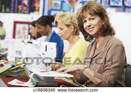 Stock Photo - Group Of Women Using Electric Sewing Machines In class. Fotosearch