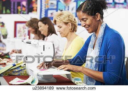 Stock Photo - Group Of Women Using Electric Sewing Machines In class. Fotosearch