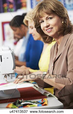Stock Photo - Group Of Women Using Electric Sewing Machines In class. Fotosearch