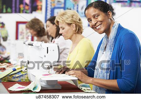 Stock Photo - Group Of Women Using Electric Sewing Machines In class. Fotosearch