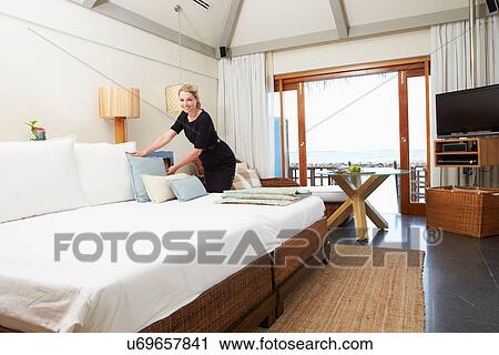 Stock Image - Hotel Chambermaid Making Guest Bed. Fotosearch