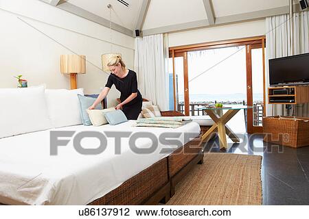 Stock Image - Hotel Chambermaid Making Guest Bed. Fotosearch