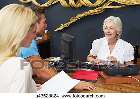 Hotel Receptionist Helping Couple To Check In View Large Photo Image Picture - Hotel Receptionist Helping Couple To Check In. Fotosearch