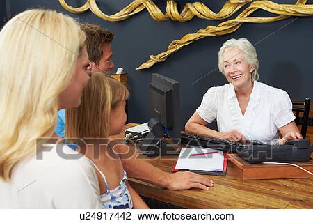 Stock Image - Hotel Receptionist Helping Family To Check In. Fotosearch
