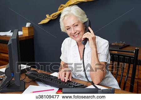 Hotel Receptionist Using Computer And Phone View Large Photo Image Stock Photo - Hotel Receptionist Using Computer And Phone. Fotosearch