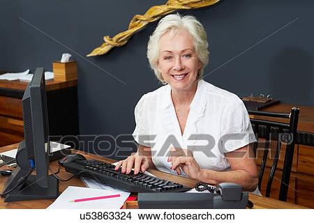 Hotel Receptionist Working At Computer View Large Photo Image Picture - Hotel Receptionist Working At Computer. Fotosearch