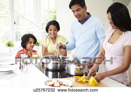 Stock Image - Indian Family Cooking Meal At Home. Fotosearch