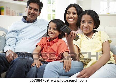 Stock Photo - Indian Family Sitting On Sofa Watching TV Together. Fotosearch
