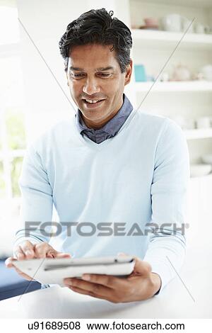 Indian Man Using Digital Tablet At Home View Large Photo Image Stock Photo - Indian Man Using Digital Tablet At Home. Fotosearch