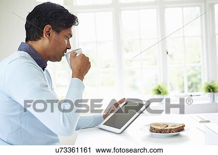 Indian Man Using Digital Tablet Whilst Eating Breakfast View Large Photo Image Stock Image - Indian Man Using Digital Tablet Whilst Eating Breakfast. Fotosearch