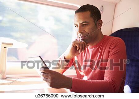 Stock Image - Man Reading E Book On Train. Fotosearch