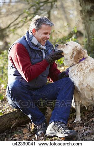 Stock Image - Man Taking Dog On Walk Through Autumn Woods. Fotosearch