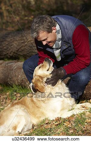 Stock Photo - Man Taking Dog On Walk Through Autumn Woods. Fotosearch