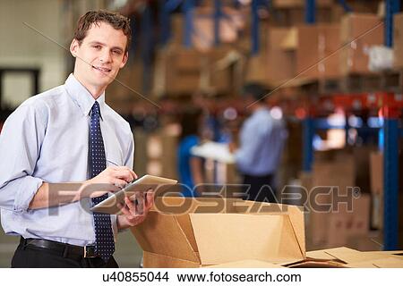 Manager In Warehouse Checking Boxes Using Digital Tablet View Large Photo Image Picture - Manager In Warehouse Checking Boxes Using Digital Tablet. Fotosearch