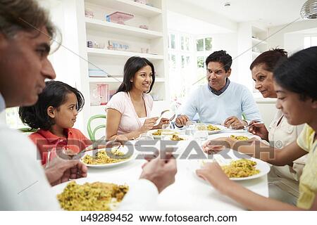 Stock Image - Multi Generation Indian Family Eating Meal At Home. Fotosearch
