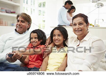 Multi-Generation Indian Family Sitting On Sofa Watching TV View Large Photo Image Stock Photograph - Multi-Generation Indian Family Sitting On Sofa Watching TV . Fotosearch