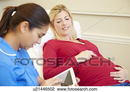 Stock Image - Nurse Using Digital Tablet In Meeting With Pregnant Woman. Fotosearch