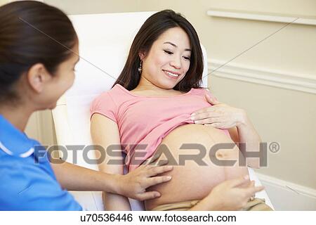 Stock Photograph - Nurse Using Digital Tablet In Meeting With Pregnant Woman. Fotosearch