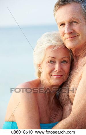 Stock Image - Portrait Of Romantic Senior Couple On Beach. Fotosearch