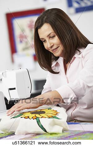 Stock Image - Portrait Of Woman Using Electric Sewing Machine. Fotosearch