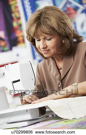 Stock Photograph - Portrait Of Woman Using Electric Sewing Machine. Fotosearch