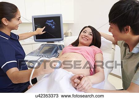 Stock Image - Pregnant Woman And Partner Having 4D Ultrasound Scan. Fotosearch