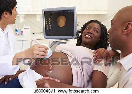 Stock Image - Pregnant Woman And Partner Having 4D Ultrasound Scan. Fotosearch