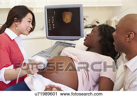Stock Image - Pregnant Woman And Partner Having 4D Ultrasound Scan. Fotosearch