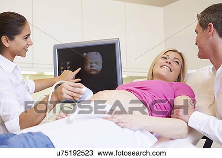 Stock Image - Pregnant Woman And Partner Having 4D Ultrasound Scan. Fotosearch